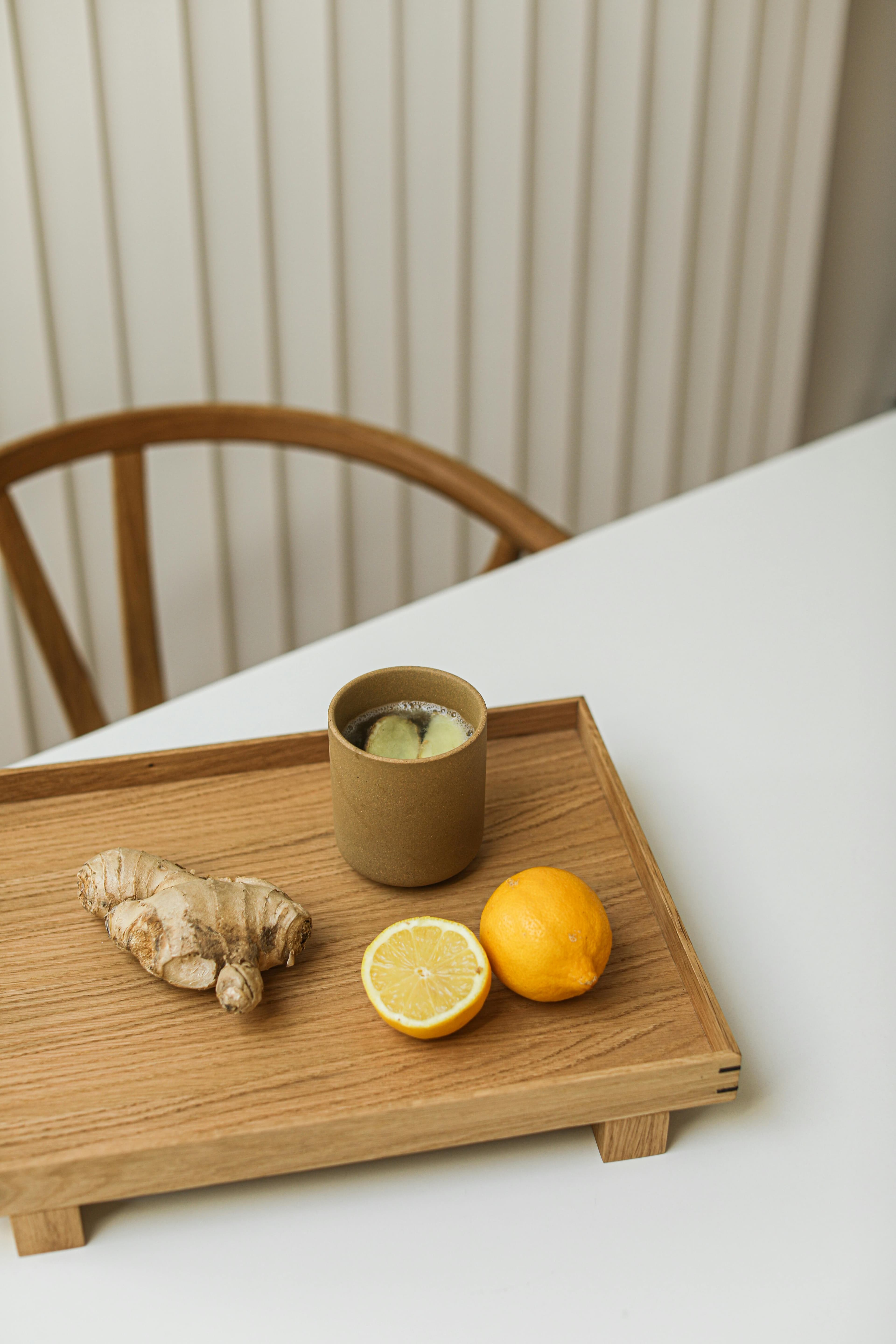 Cup of herbal tea with ginger and lemon on a wooden tray