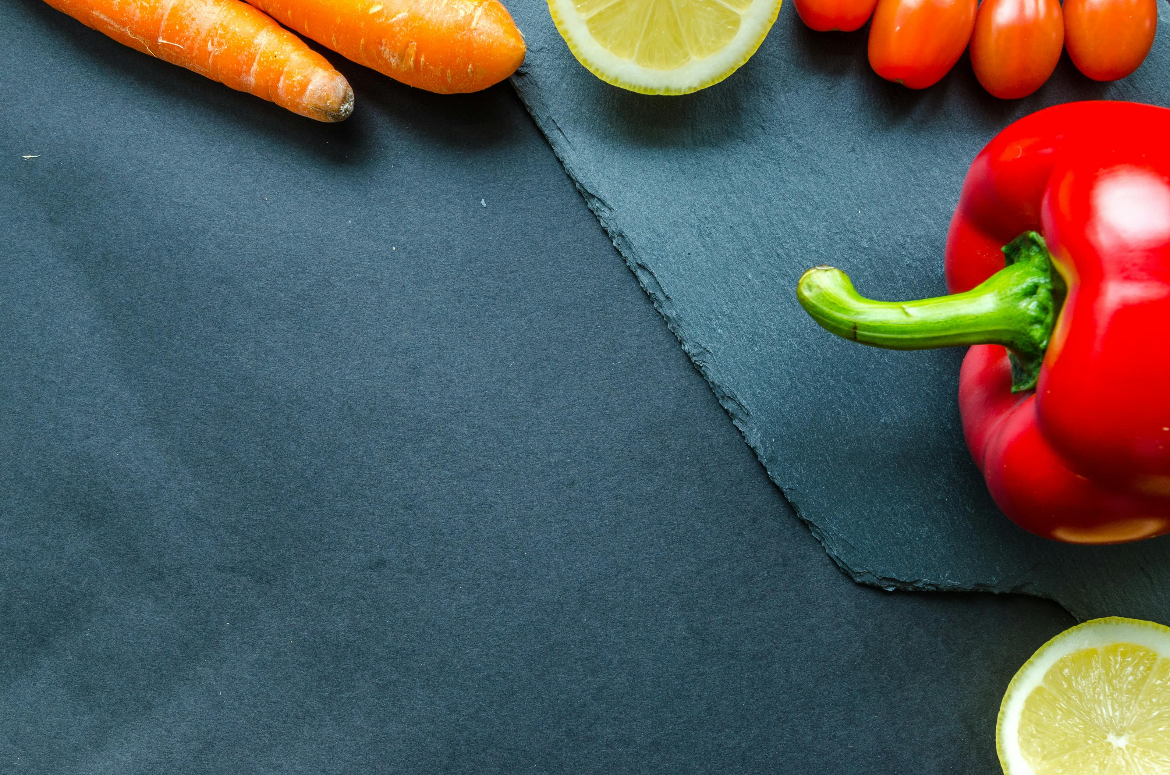 Fresh vegetables and fruit arranged on a slate surface